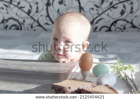 A little boy celebrates Easter, sits at a wooden table and eats