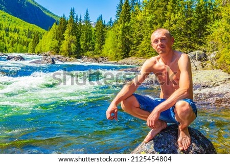 Young male traveler and tourist on a huge rock in the river water of the Rjukandefossen in Hemsedal Viken Norway the most beautiful waterfall in Europe.