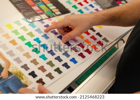 Cropped man hand choosing samples catalog multicolor advertising T-shirts palette film membrane. Textile production Royalty-Free Stock Photo #2125468223