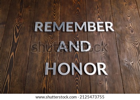 words remember and honor laid with silver metal letters on wooden background in linear perspective