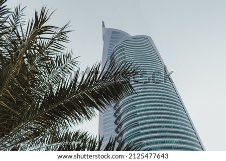 Daytime modern skyscraper business tower and residential building with blue sky and palm tree