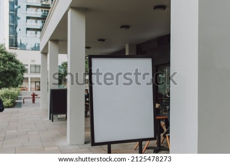 Blank signboard display signage with black frame standing outdoor near cafe on the street