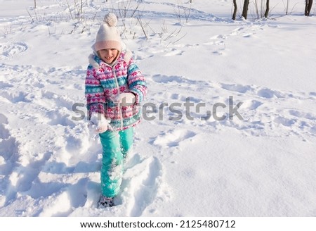 happy beautiful little girl of seven eight years walking in winter snowy park