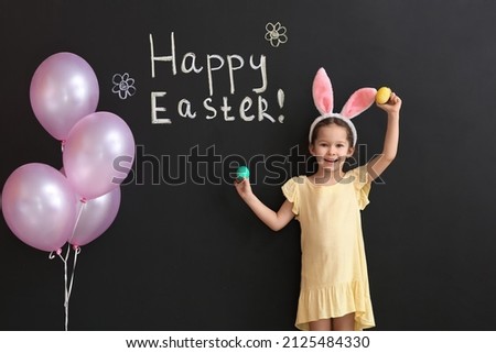Funny little girl with bunny ears and Easter eggs on dark background