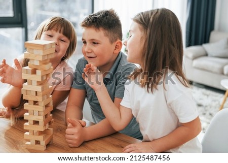 Building a tower. Playing game. Kids having fun in the domestic room at daytime together.