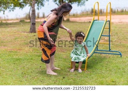 little girl in a dress plays with her mother on the playground