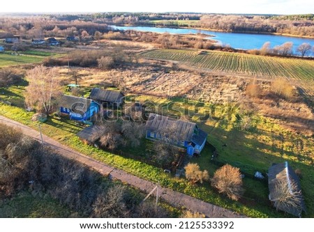 Wooden home in village at lake. Country houses in the countryside. Aerial view of roofs of rural homes. Suburban house at countryside. Rural housing outside the city. Russian region in countryside.