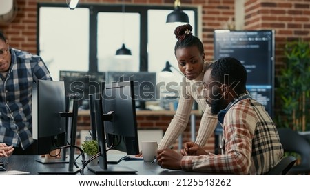 Mixed team of programmers brainstorming ideas for new cloud computing user interface looking at running code on computer screens. Developers collaborating on group project compiling algorithm. Royalty-Free Stock Photo #2125543262