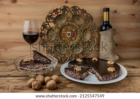 Matzo chocolate cake, Passover plate and red wine  for Jewish Pesach holidays. Selective focus. English translation from Hebrew : Passover ( plate center).