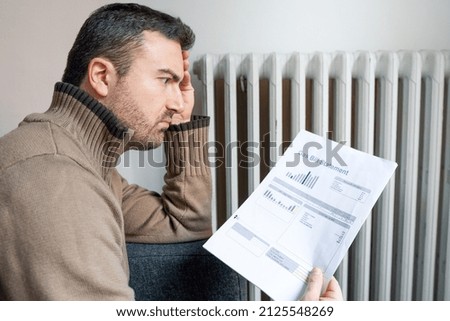 Shocked man reading some utilities bills home heating expenses