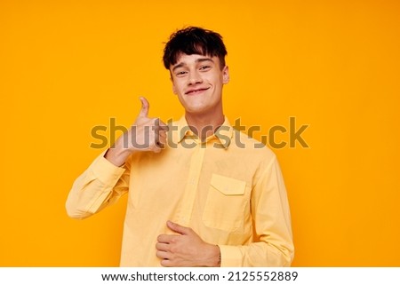 Cheerful young man in a yellow shirt gestures with his hands emotions