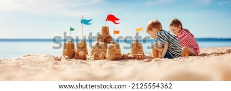 Boy and girl playing on the beach on summer holidays. Children building a sandcastle at the sea. Royalty-Free Stock Photo #2125554362