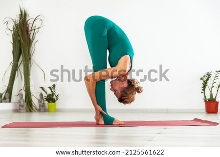 Young woman yogi stretches in yoga studio. Practicing yoga indoors