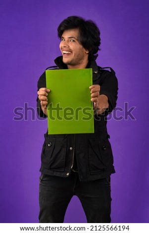 Young happy man holding and posing with the book on background.
