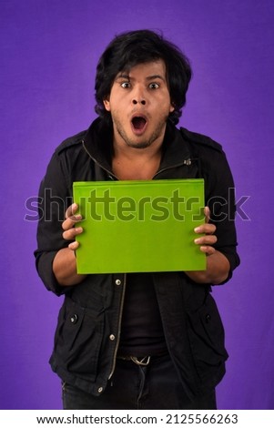 Young happy man holding and posing with the book on background.