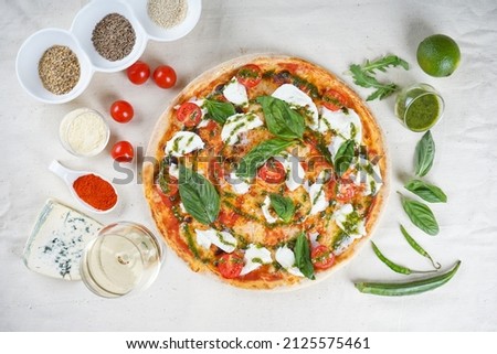 vegetarian pizza with cheese tomatoes and basil with pesto sauce on a white plate with ingredients
 Royalty-Free Stock Photo #2125575461