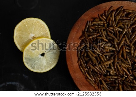 a food that is usually eaten in rural areas, this food is called dried maggot served on a wooden plate