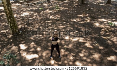 Young woman stretching before workout at a park outdoors. Athlete female person prepping for workout. Drone view. Feel good, healthy concept. High quality photo
