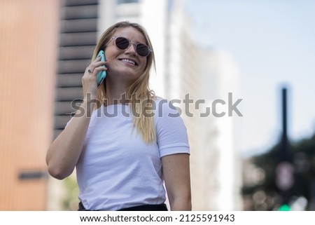 Young woman using a smartphone at day time with city view landscape in the background. High quality photo. Mobile phone, technology, urban concept. 