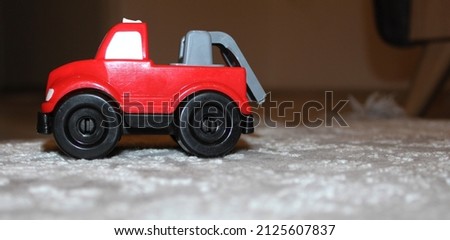 photo of toy fire truck for babies with black wheels and red color on the carpet