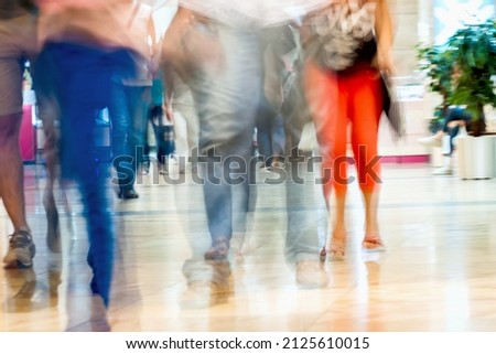 Abstract defocused motion blurred young people walking in the shopping center. For background , backdrop, substrate, composition use.
