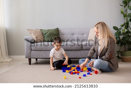 family pastime mom and son play cubes on the carpet near the sofa in the room