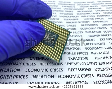 Gloved hand keeping a microprocessor with a text containing recession, economic crises, inflation on background