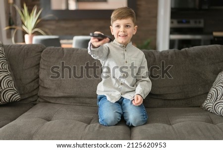 A boy watching television sit on the sofa at home