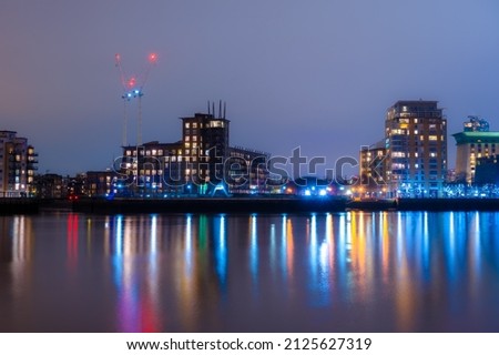 Panoramic view of the Rotherhithe residential buildings reflected in the Thames River at night, in London