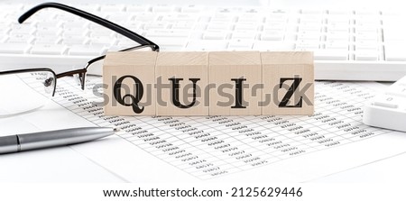 QUIZ written on wooden cube with keyboard , calculator, chart,glasses.Business