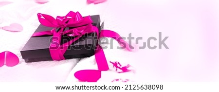 Gift box packed and postcard decorated with a red beautiful bow on the bed. Valentine's day, Birthday love gift. Weeding, honeymooners concept. Lovers or romantic Banner.Selective focus