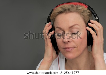woman with headphones listening to music with grey background stock photo 
