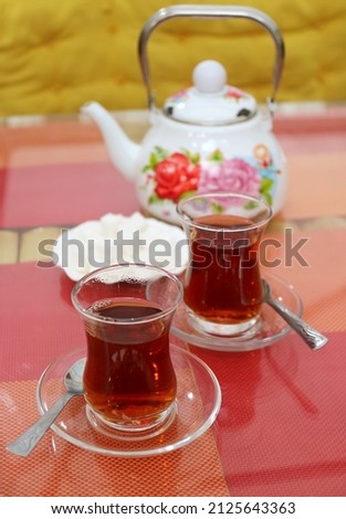 Two Glasses of Hot Turkish Tea with Blurry Teapot and Sugar Cubes in the Backdrop