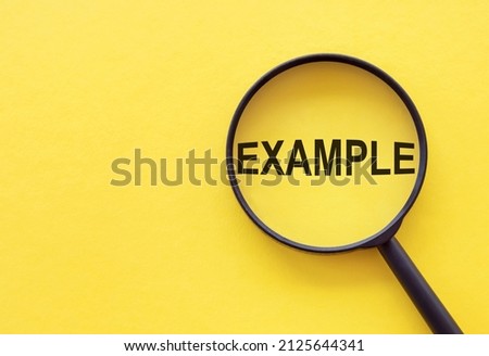 The word EXAMPLE is written on a magnifying glass on a yellow background. Royalty-Free Stock Photo #2125644341