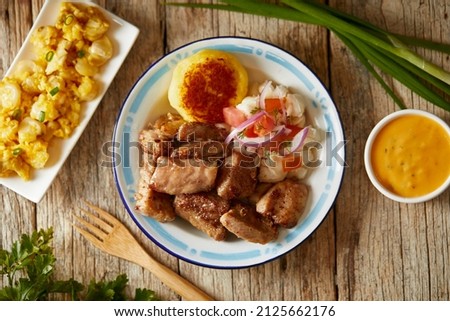 Homemade fritada a typical ecuadorian dish that consists on braised pork. It’s served on a white plate with motepillo and with a traditional and wooden background  Royalty-Free Stock Photo #2125662176