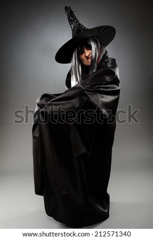 Full length of a sorcerer with hat and cape over gray background