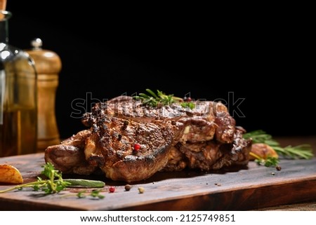 Cooked juicy steak meat beef with seasoning on wooden chopping board. Royalty-Free Stock Photo #2125749851