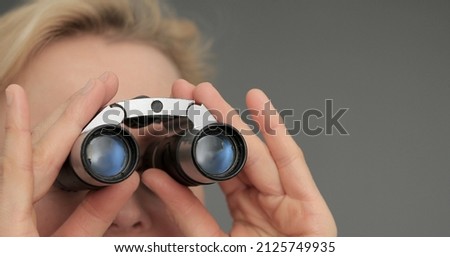 Woman looking through toy binoculars toilet paper roll on grey background stock photo
