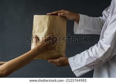 Side view of Muslim hands sharing rice alms bags isolated on black background. Royalty-Free Stock Photo #2125764983