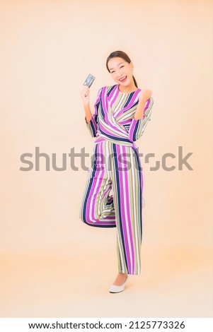 Portrait beautiful young asian woman with smart mobile phone and credit card on color isolated background