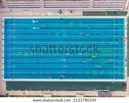 Aerial view of group of swimmers training in swimming pool. Many sportive people swim in Open Water Swimming pool.