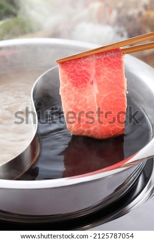chopsticks holding sliced beef in to shabu hot pot
 Royalty-Free Stock Photo #2125787054