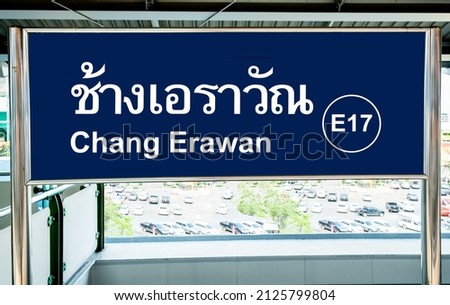 Blue sign in Thai and English languages in a train station on the Bangkok BTS skytrain Royalty-Free Stock Photo #2125799804
