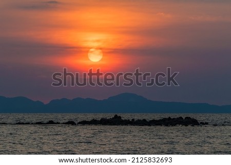 Sunset over the mountain ridge and the sea rocks