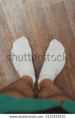 Hairy male legs on the floor in short white socks