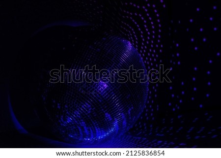 Rays of bright blue and purple light on the floor and walls. Disco ball reflecting light in a dark hall for discos. Dark photo. Copy space.