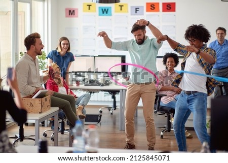 Two male employees is playing with hula-hoop in a relaxed atmosphere in the office with their colleagues. Employees, job, office Royalty-Free Stock Photo #2125845071