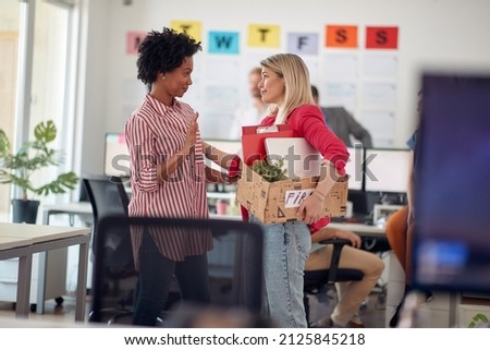 A young female clerk in a sad atmosphere in the office says goodbye to a colleague after she was fired. Employees, job, office Royalty-Free Stock Photo #2125845218