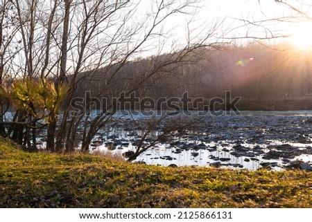 View of a beautiful evening sunset on the background of a green lawn and a river.