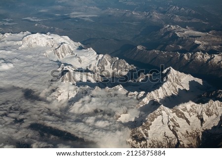 Aerial photo of the Mont Blanc massif in the Alps with the snow-covered Aiguille Verte and Mont Dolent peaks and France-Italy-Switzerland tripoint on the right. View from a plane flying over the Alps.